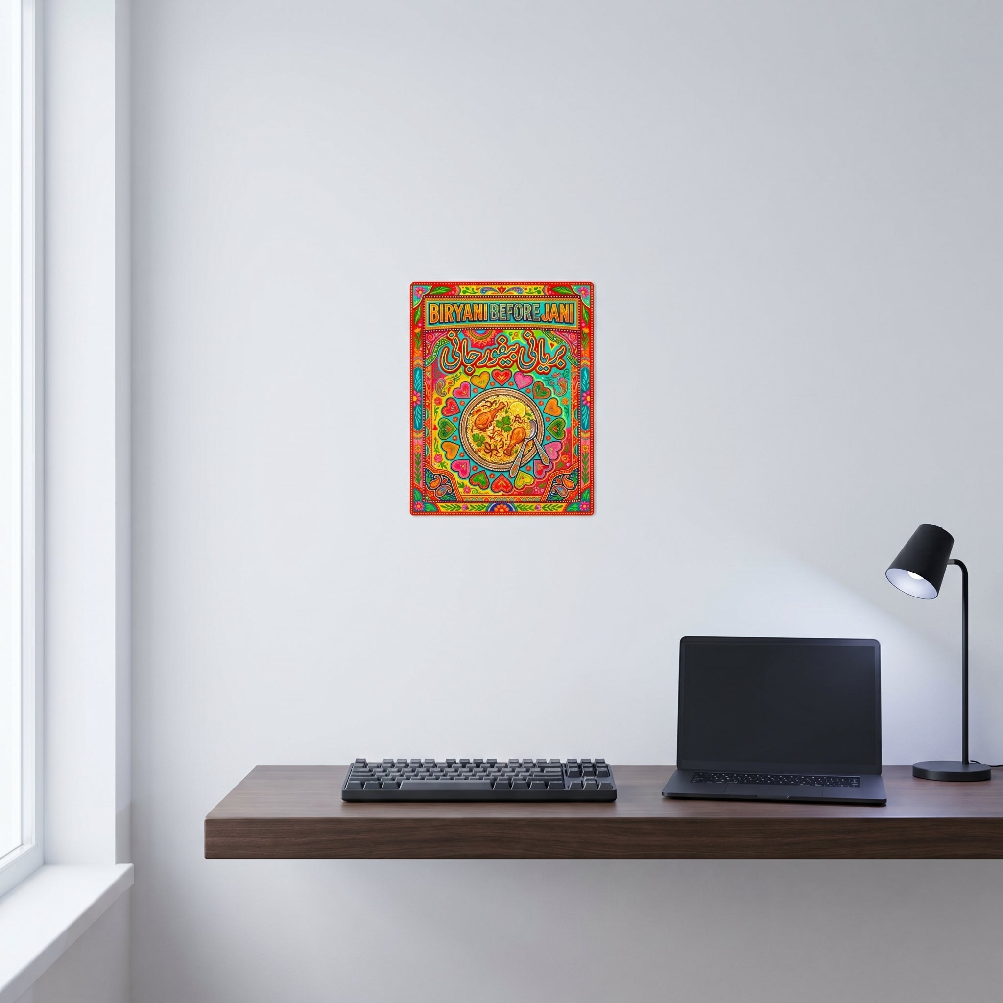 Funny Urdu food culture art print displayed neatly on a white wall behind a modern minimalist computer workspace with a desk lamp
