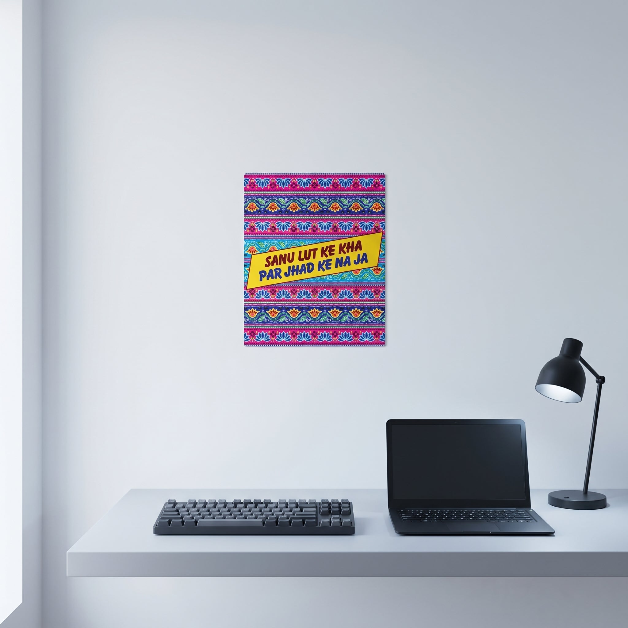 Traditional style South Asian poetry poster displayed on a crisp white wall behind a minimalist home office desk setup.
