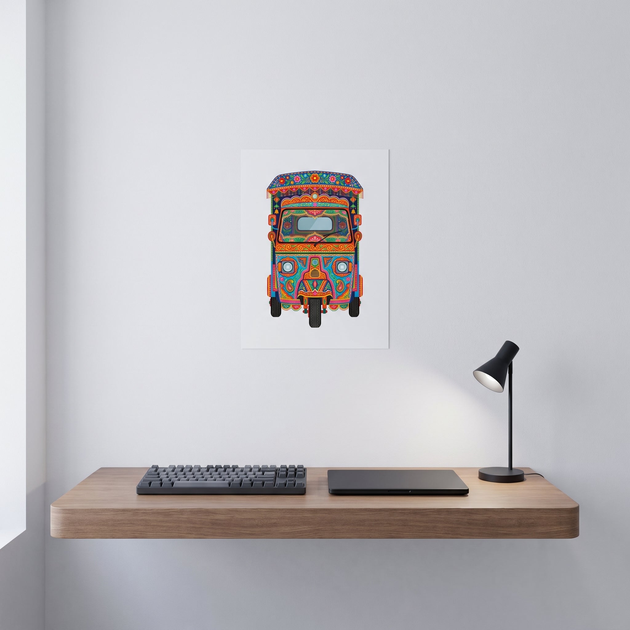 Vibrant Pakistani folk art statement sign styled on a crisp white wall behind a minimalist home office desk setup with a keyboard.