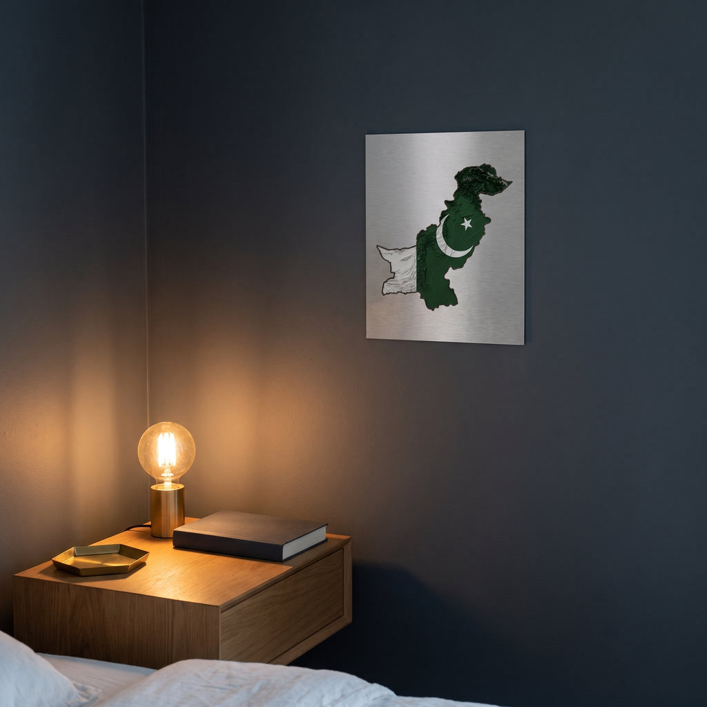 Modern 3D terrain map of Pakistan print displayed on a dark charcoal grey accent wall over a sleek wooden console floating cabinet.
